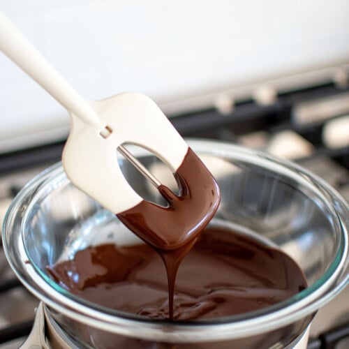 melted dark chocolate in a double boiler on the stove with a candy thermometer in it.