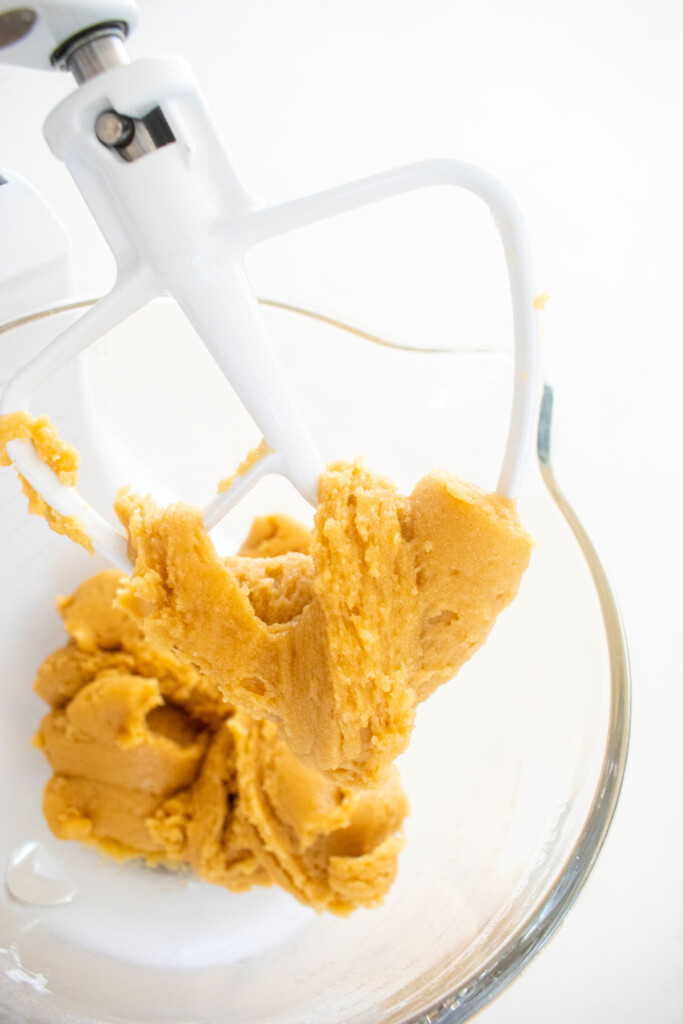 brown butter cookie dough in a glass mixing bowl on a marble counter.