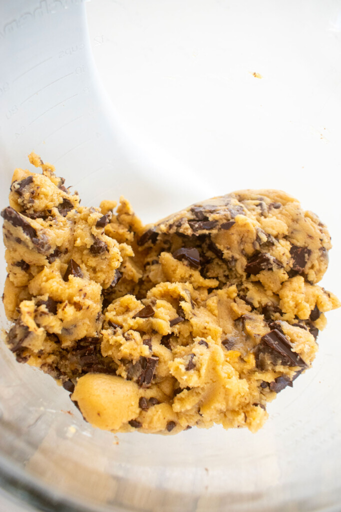 brown butter caramel dark chocolate cookie dough in a glass mixing bowl on a marble counter.