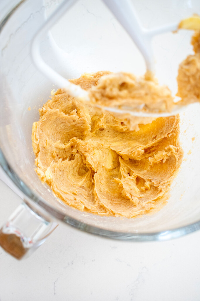 creamed butter brown sugar and coconut oil in a glass mixing bowl on a marble counter.