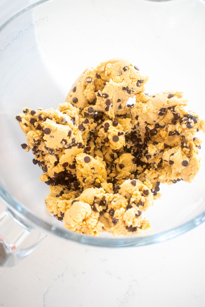 brown sugar chocolate chip mini cookie dough in a glass mixing bowl on a marble counter.