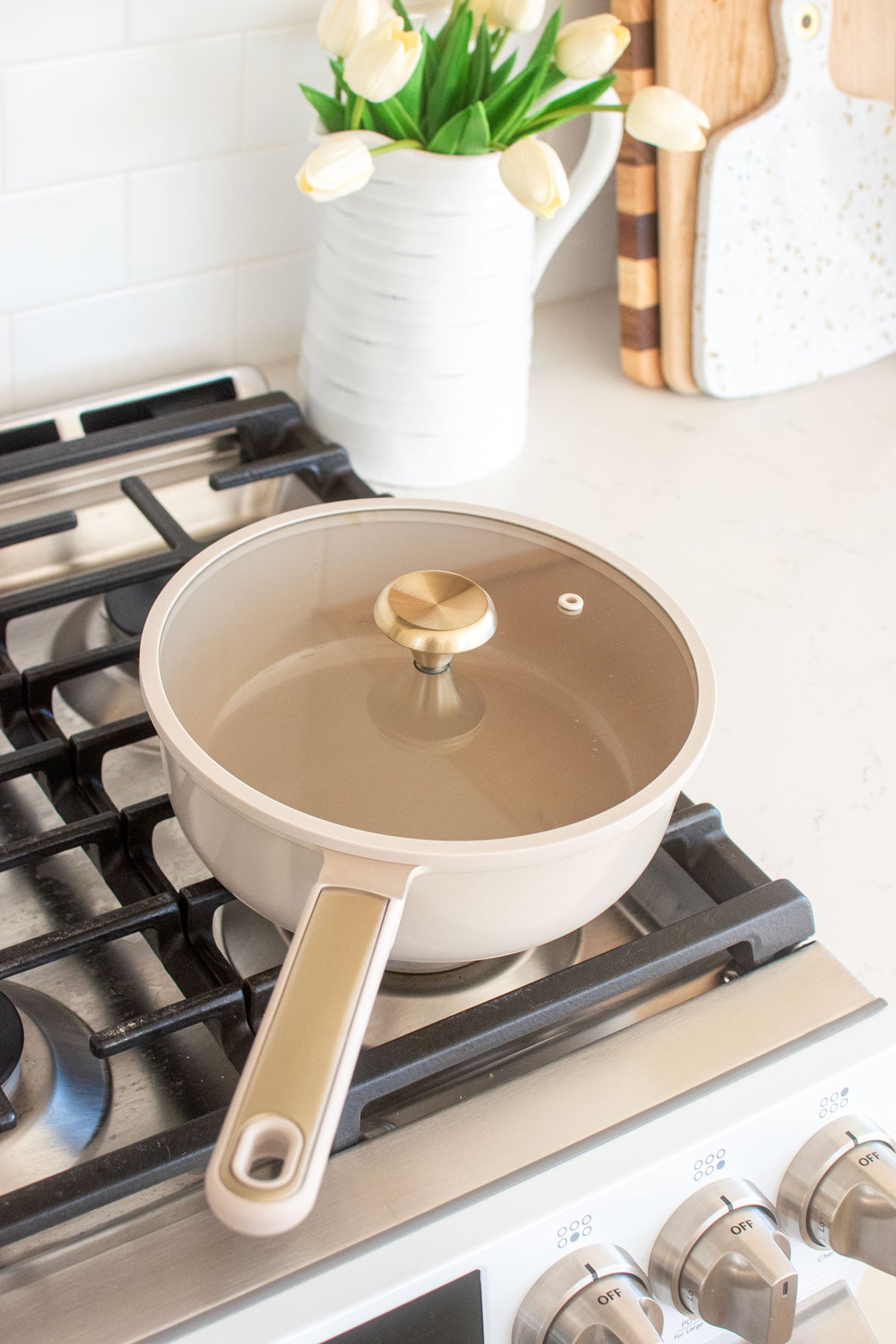 taupe carote pan with a gold knob on top of a stove.