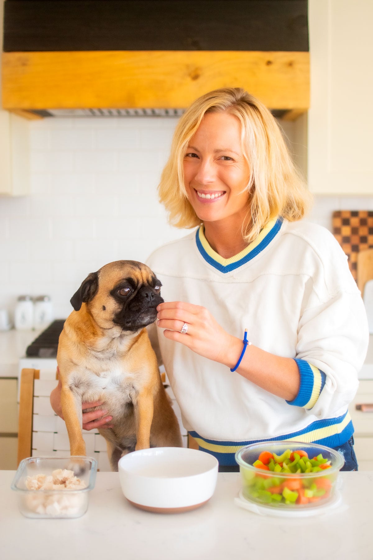 woman and pug at kitchen counter making dinner.