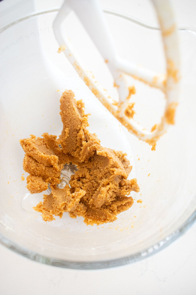 creamed butter and sugar in a glass stand mixing bowl on a white marble counter.