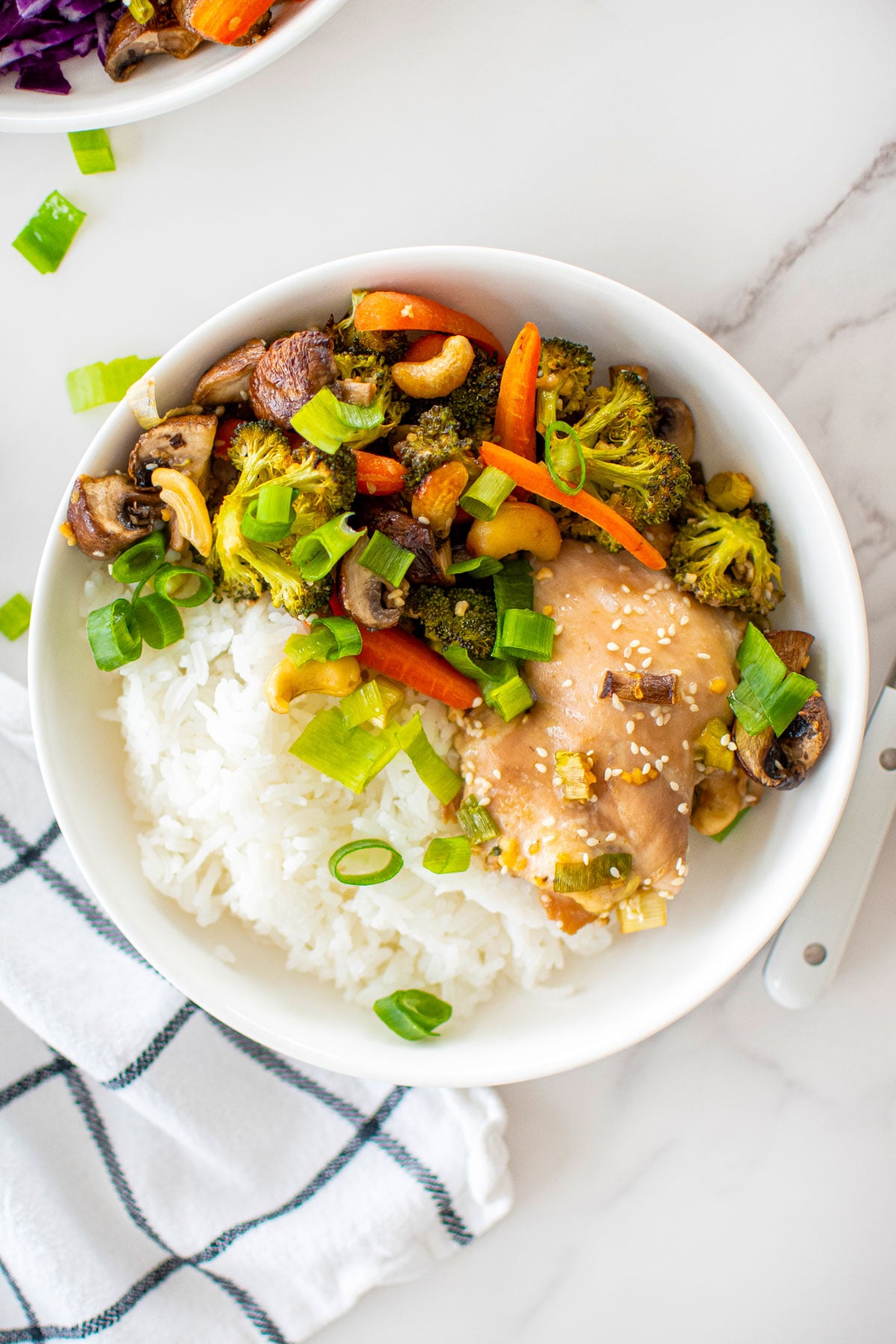 honey garlic chicken sheet pan dinner in a bowl on a white marble counter.