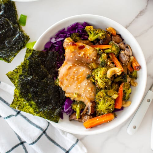 honey garlic chicken sheet pan dinner in a bowl on a white marble counter.