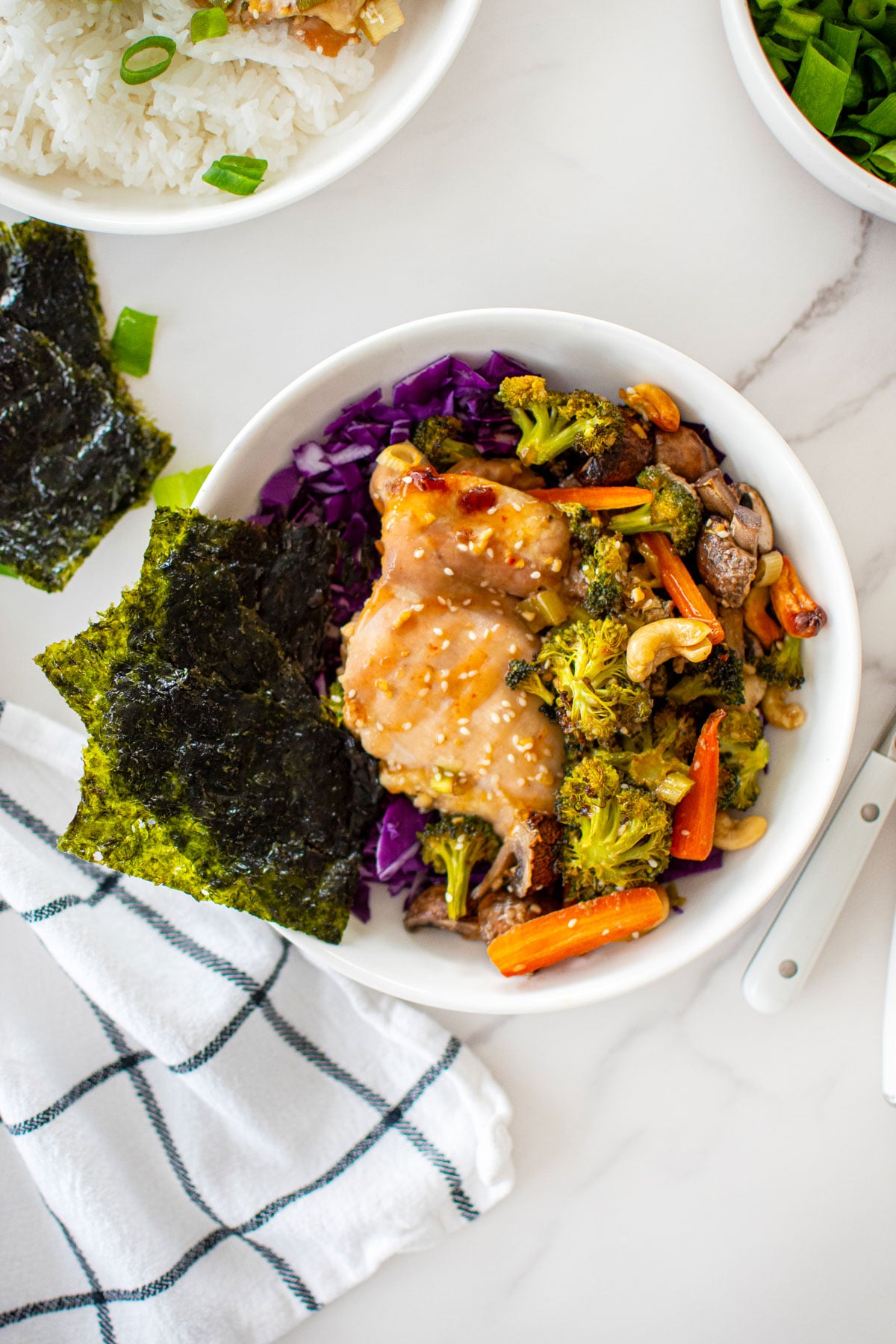 honey garlic chicken sheet pan dinner in a bowl on a white marble counter.