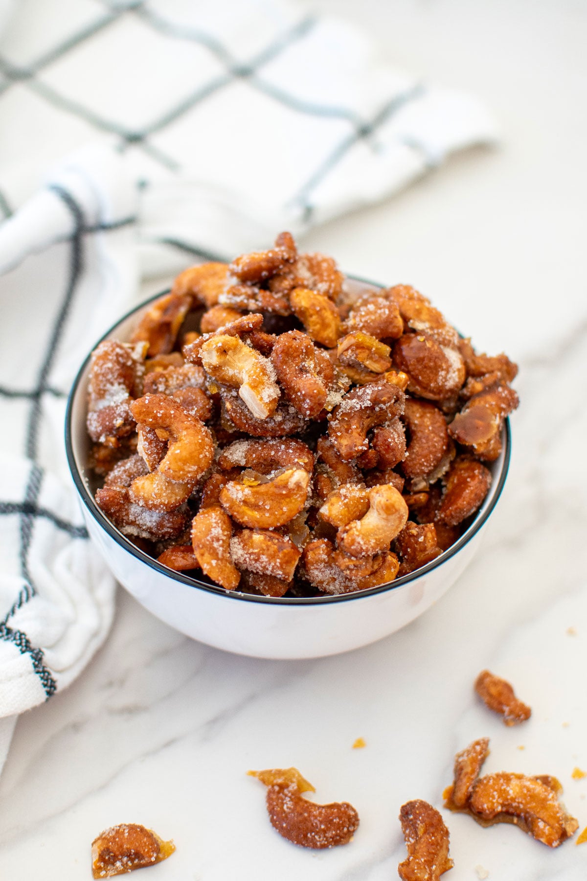 honey roasted cashews in a bowl on a white marble countertop.