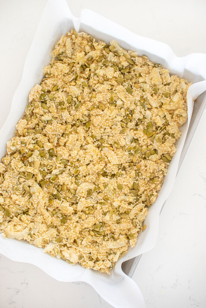 honey sesame dark chocolate bark spread onto a baking sheet on a white marble countertop.