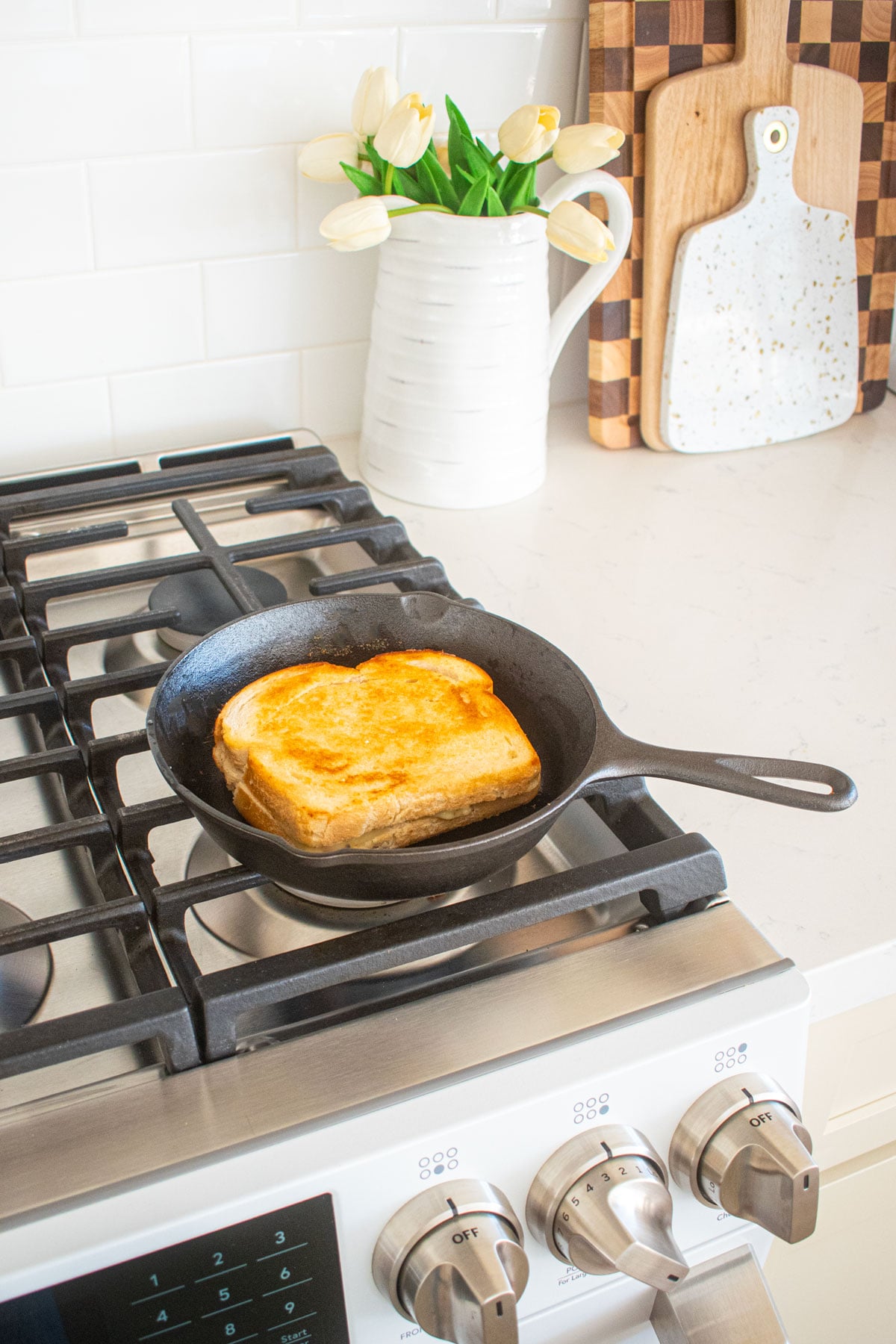 lodge cast iron skillet with a grilled cheese being cooked on a stovetop.