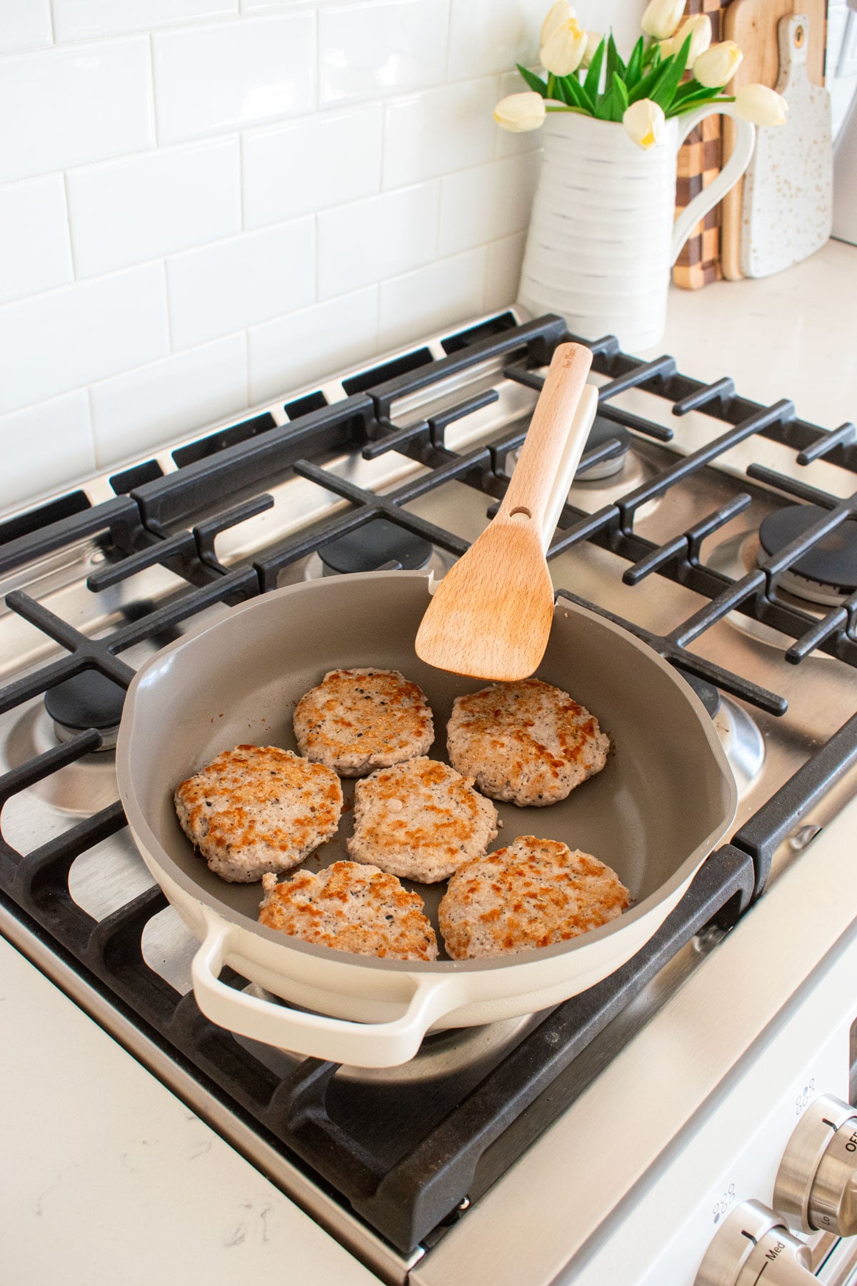 our place always pan with turkey breakfast sausages being cooked on top of a gas stove top.