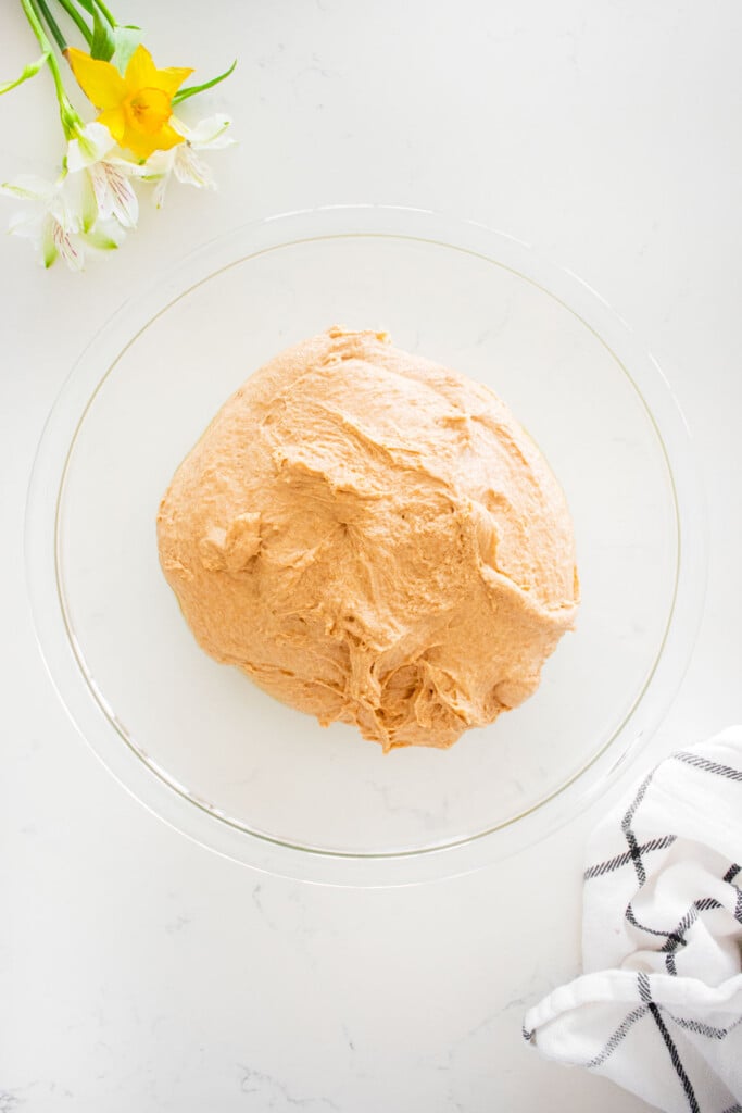 large glass mixing bowl with sourdough discard whole wheat sandwich bread dough on a marble counter.