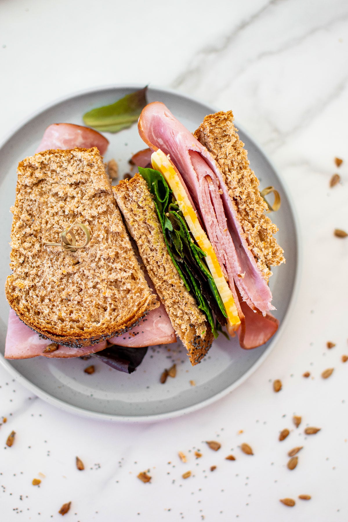 sourdough discard whole wheat sandwich bread made with a sandwich on a gray plate on a white marble counter.