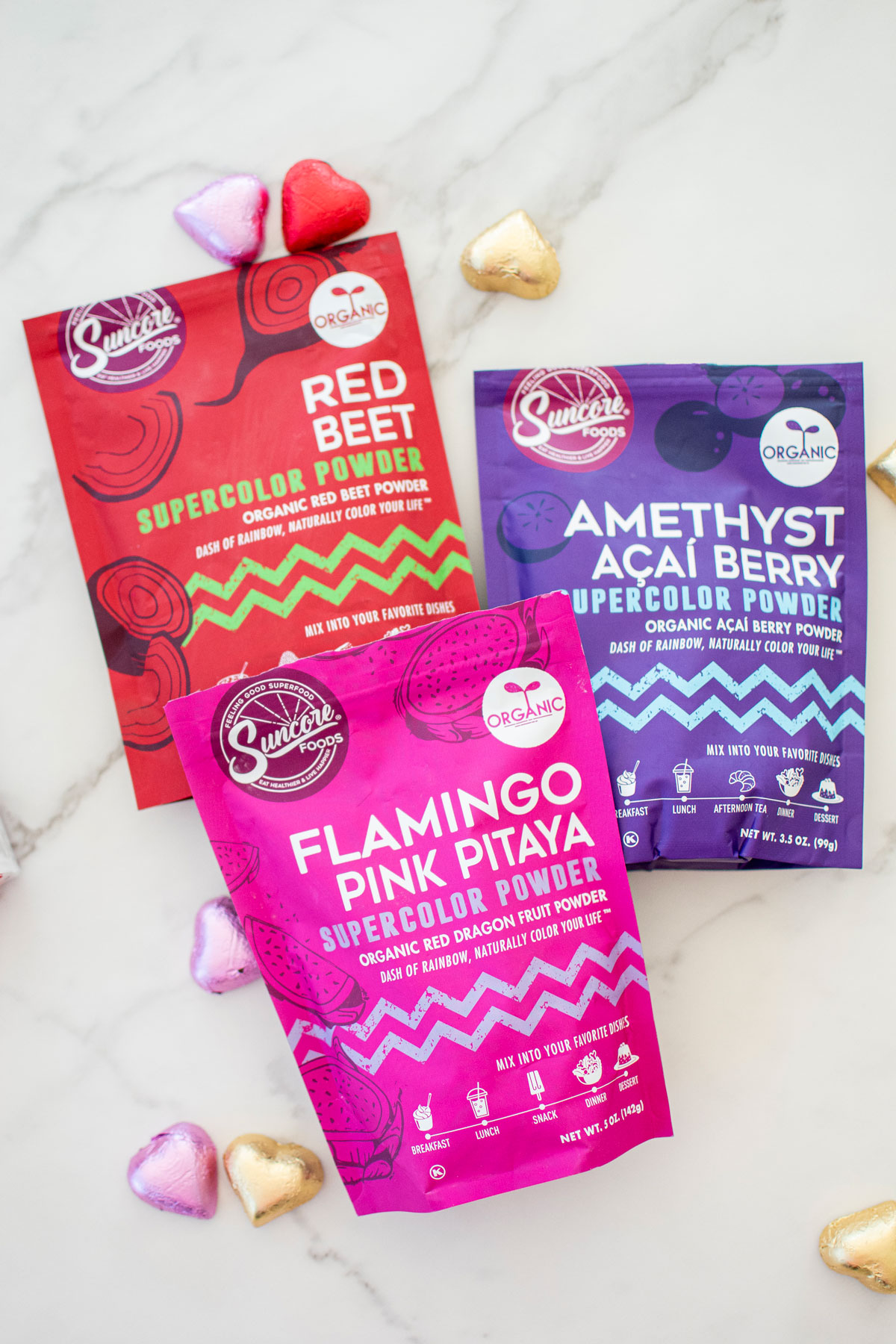 valentine's day organic food dyes in pink, red and purple on a white marble counter.
