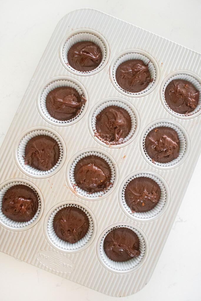 chocolate cupcake batter in a cupcake pan on a white marble counter.