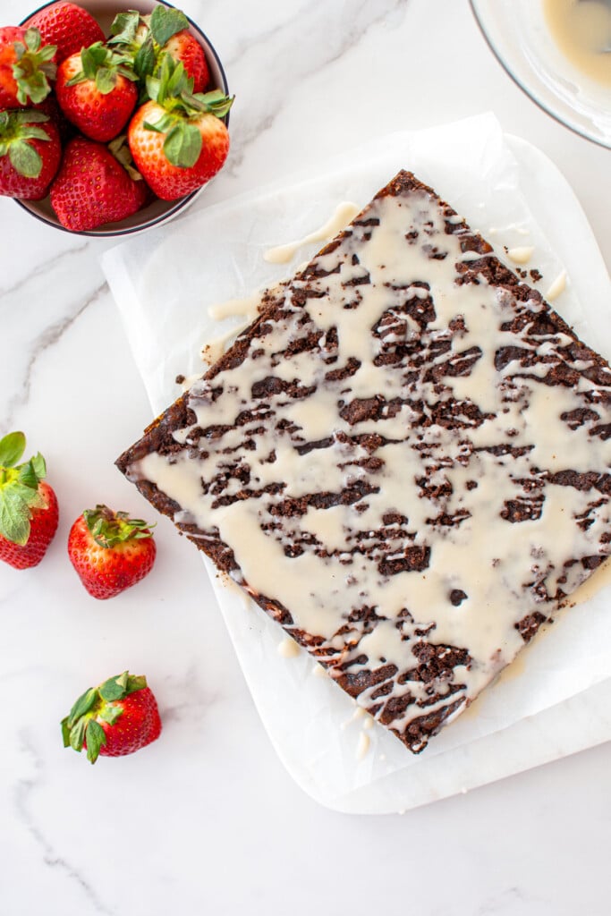 chocolate strawberry crumb bars drizzled with glaze on a white marble counter.
