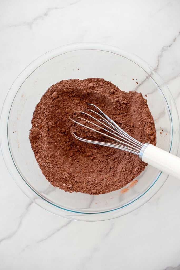 dry ingredients for chocolate strawberry crumb bars whisked together in a glass mixing bowl on a white marble counter.