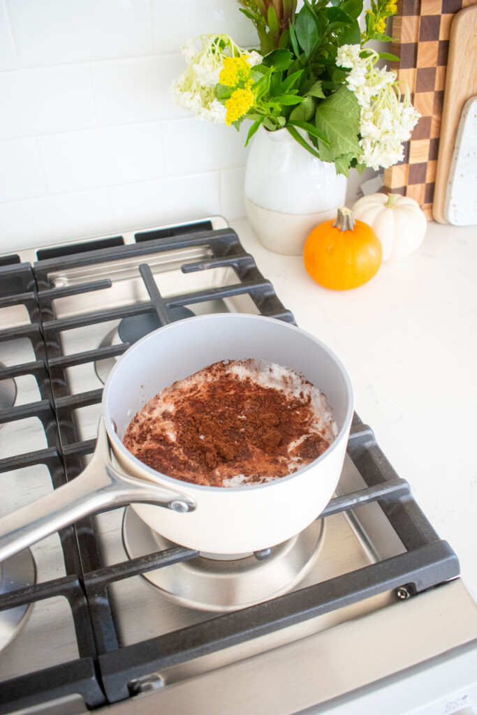 coconut hot chocolate heating in a small pot on the stovetop.