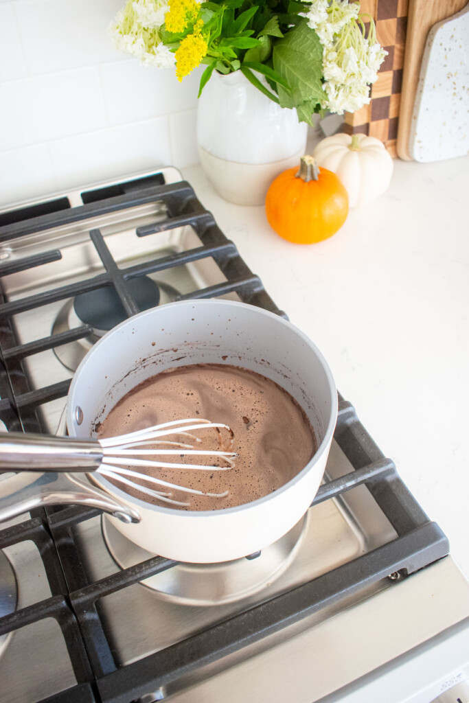 coconut hot chocolate heating in a small pot on the stovetop.