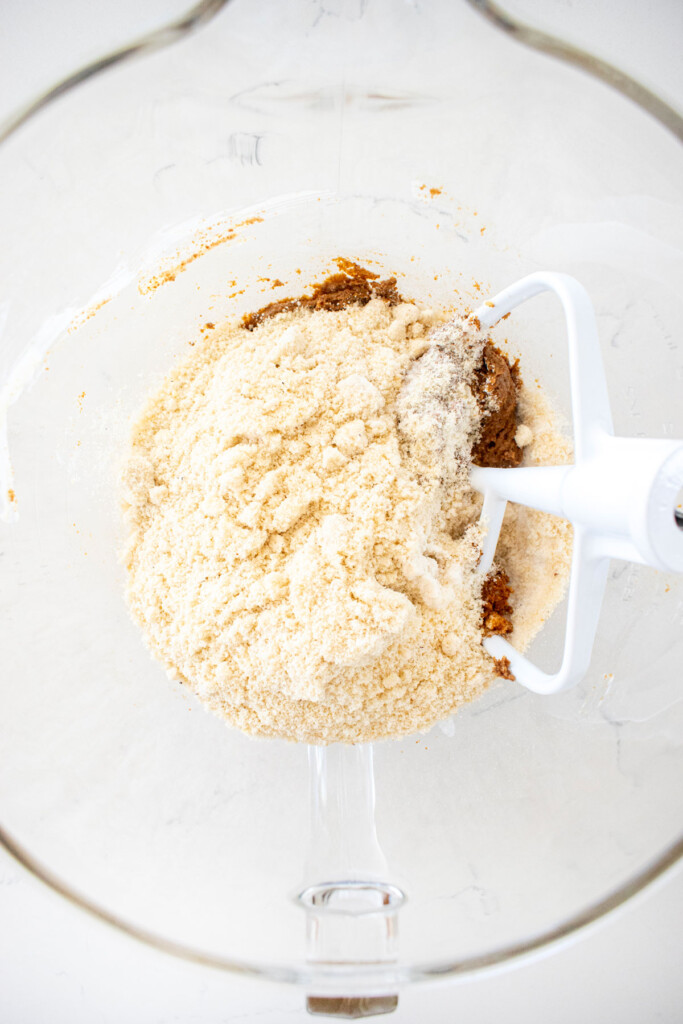 ingredients for healthy chocolate chip cookie dough in a glass mixing bowl on a marble counter.