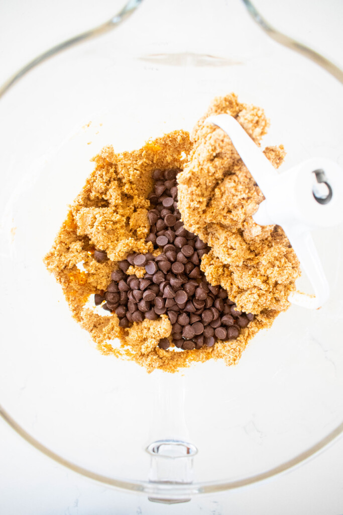 healthy chocolate chip cookie dough in a glass mixing bowl on a marble counter.