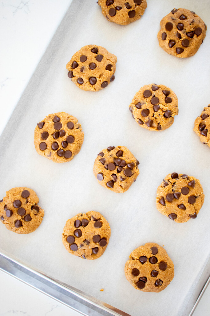 healthy chocolate chip cookie dough balls on a baking sheet on a marble counter.