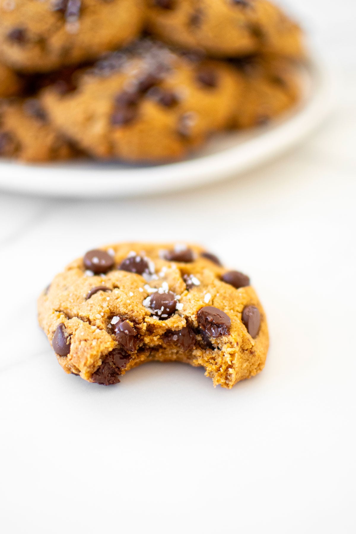 healthy chocolate chip cookie with coconut sugar on a marble counter with a bite taken out.