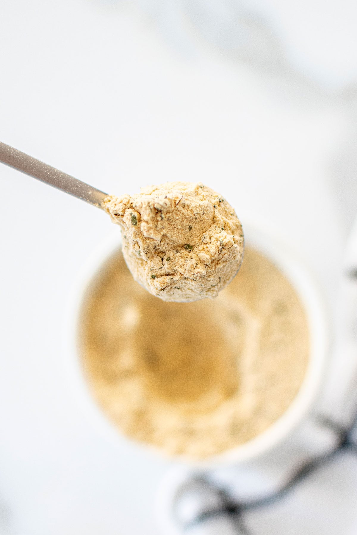 spoon of homemade ranch seasoning coming out of a bowl on a white marble countertop.