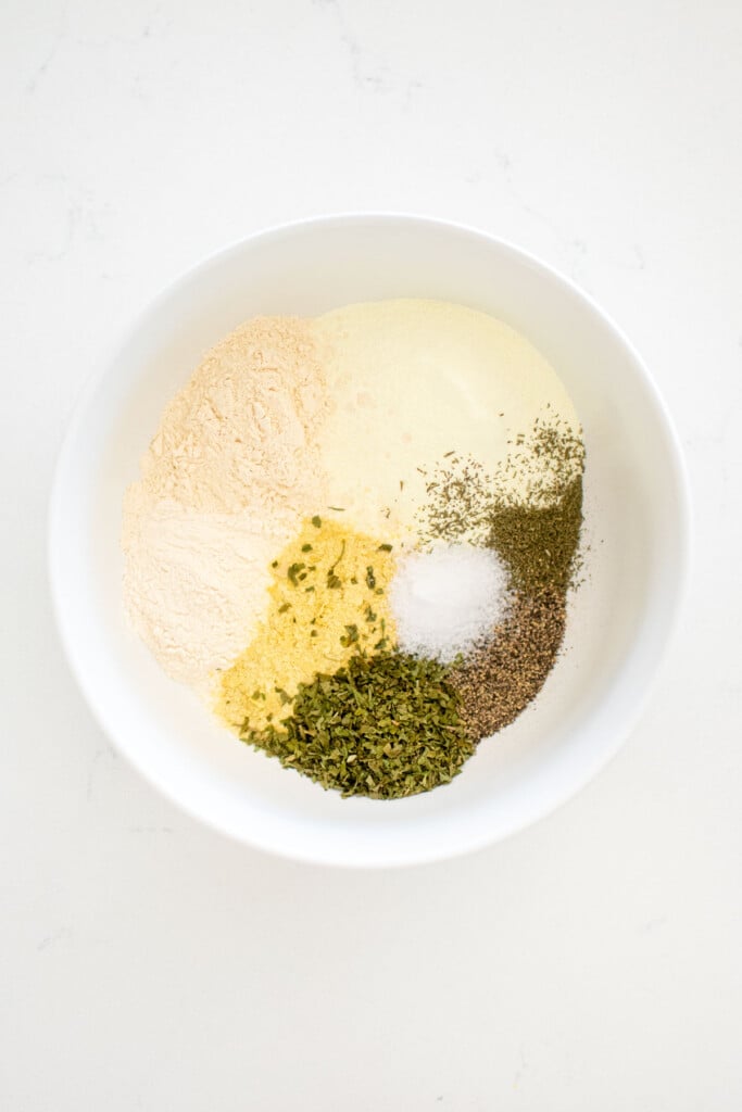 spices for homemade ranch seasoning in a bowl on a white marble countertop.