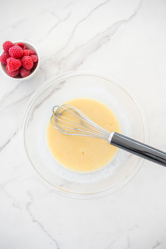 wet ingredients for small batch chocolate cake with sourdough discard whisked together in a glass mixing bowl on a white marble countertop.
