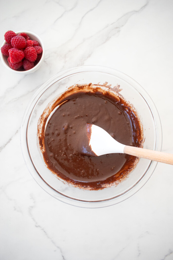 ingredients for small batch chocolate cake with sourdough discard in a glass mixing bowl on a white marble countertop.