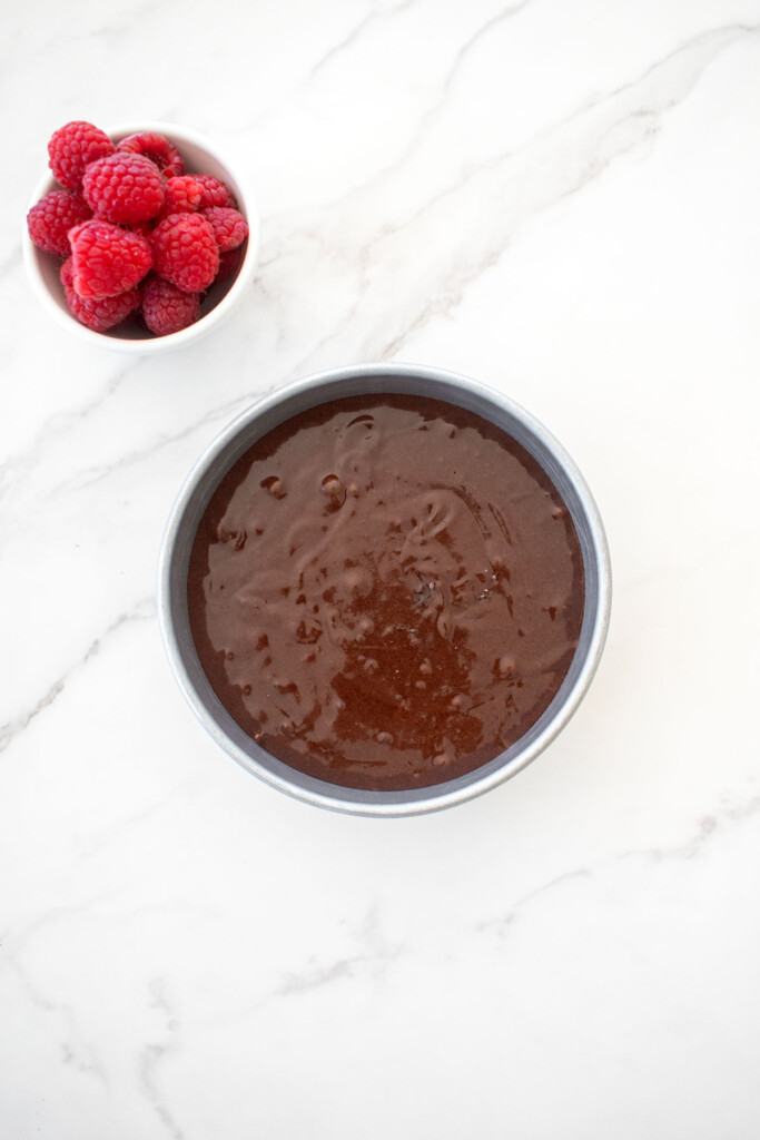 small batch chocolate cake with sourdough discard batter in a cake pan on a white marble countertop.