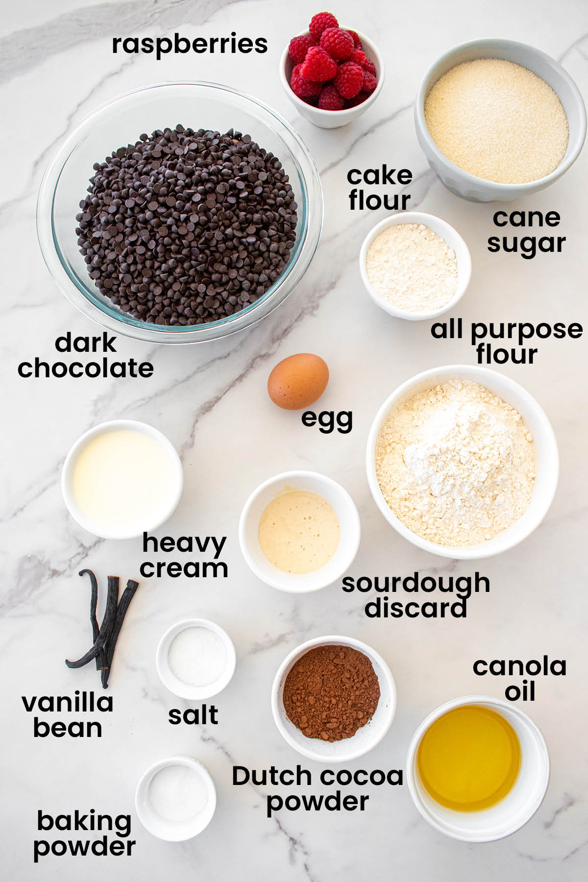 individual ingredients for small batch chocolate cake with sourdough discard laid out against a white background.