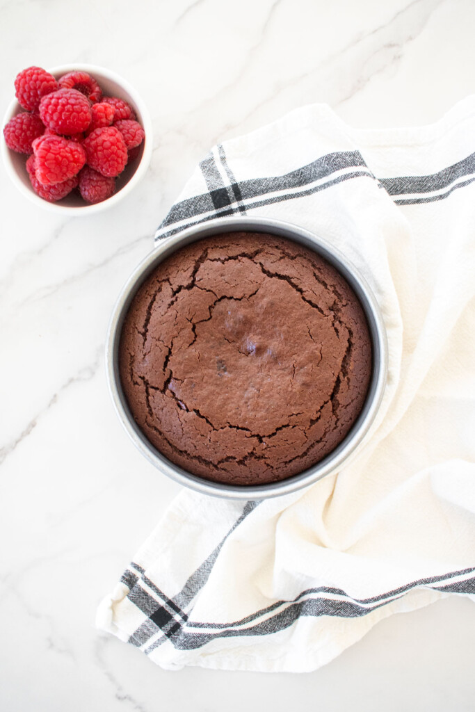 small batch chocolate cake with sourdough discard baked in a cake pan on a white marble countertop.
