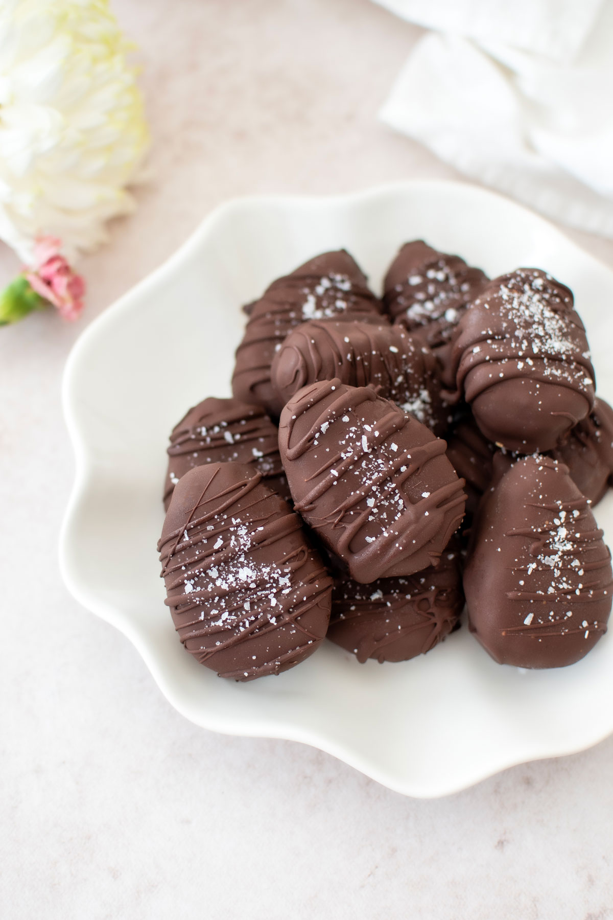 dark chocolate coconut almond butter eggs with flaky sea salt on a ruffle plate.