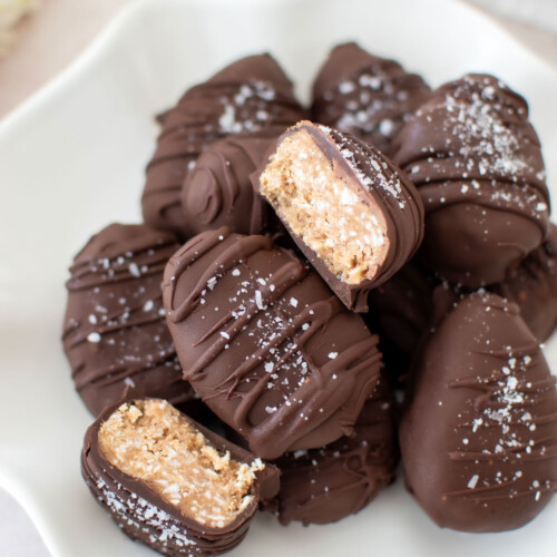 dark chocolate coconut almond butter eggs on a plate, one cut in half to reveal the center.