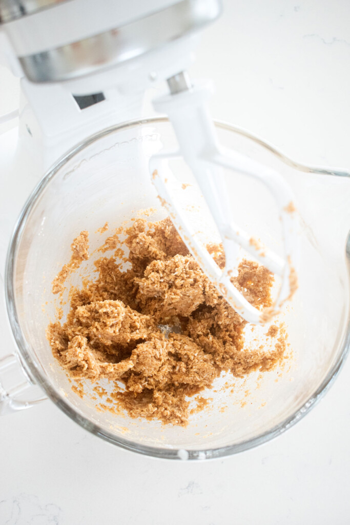 coconut almond butter egg filling mixed in a glass stand mixing bowl on a white marble counter.