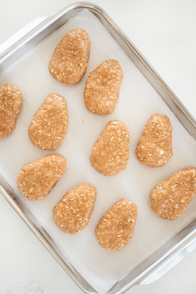 coconut almond butter eggs shaped on a baking sheet on a marble counter.