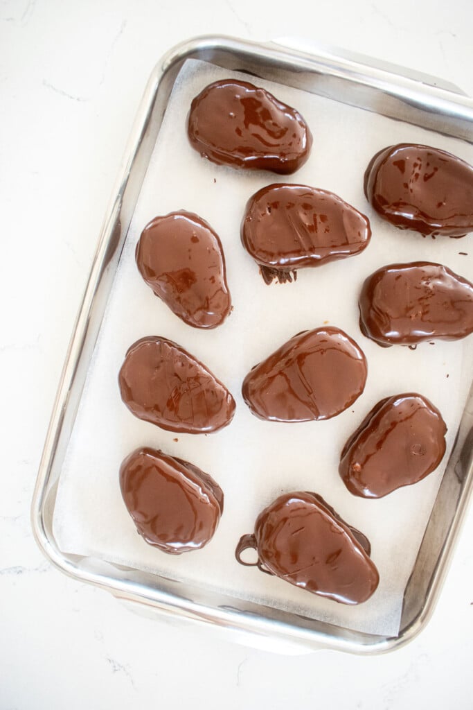 dark chocolate coconut almond butter eggs dipped in chocolate on a baking sheet.