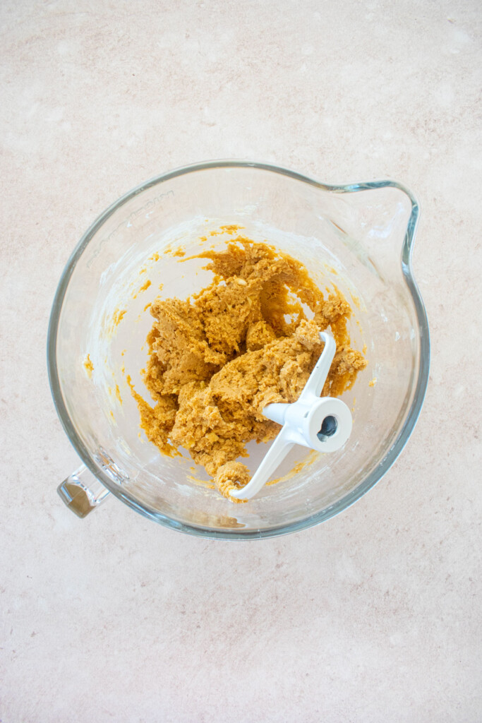 easter banana blondies dough in a glass mixing bowl on a pink counter.
