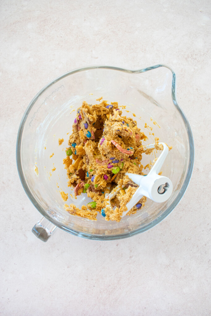 easter banana blondie dough in a glass stand mixing bowl on a light pink counter.