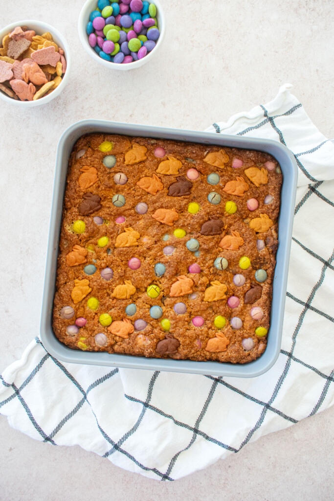 baked easter banana blondies in a square baking pan on a light pink counter.