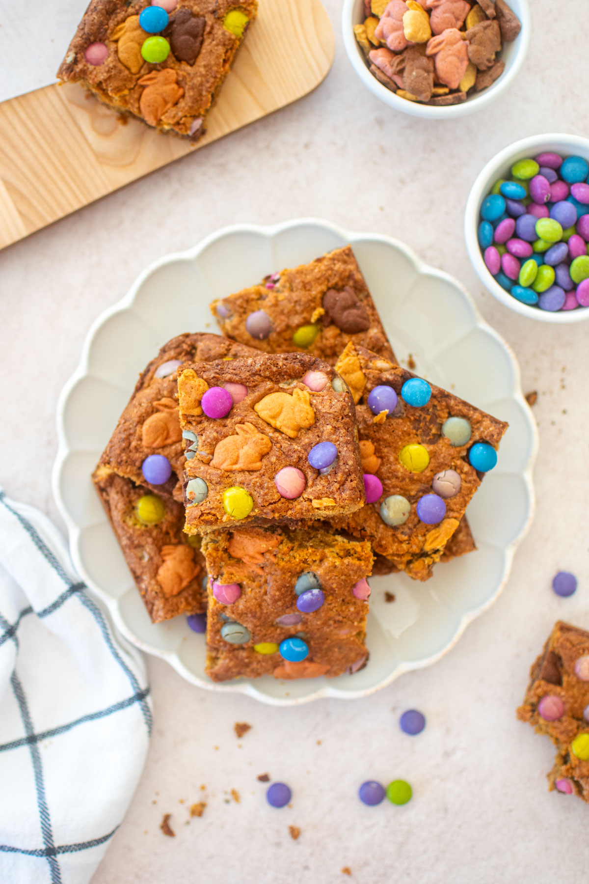 easter banana blondies cut into squares on a ruffle plate on a pink counter.