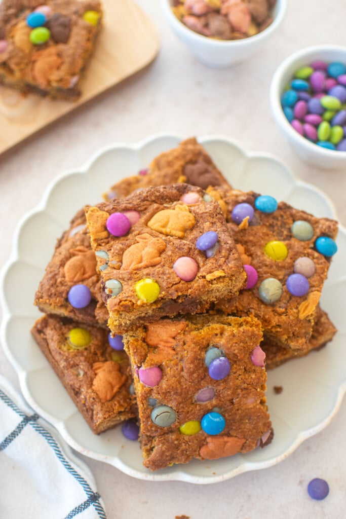 easter banana blondies cut into squares on a ruffle plate on a pink counter.