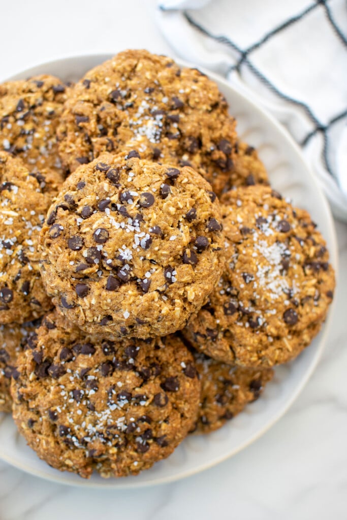 a plate of pumpkin oatmeal chocolate chip cookies on a white marble countertop.