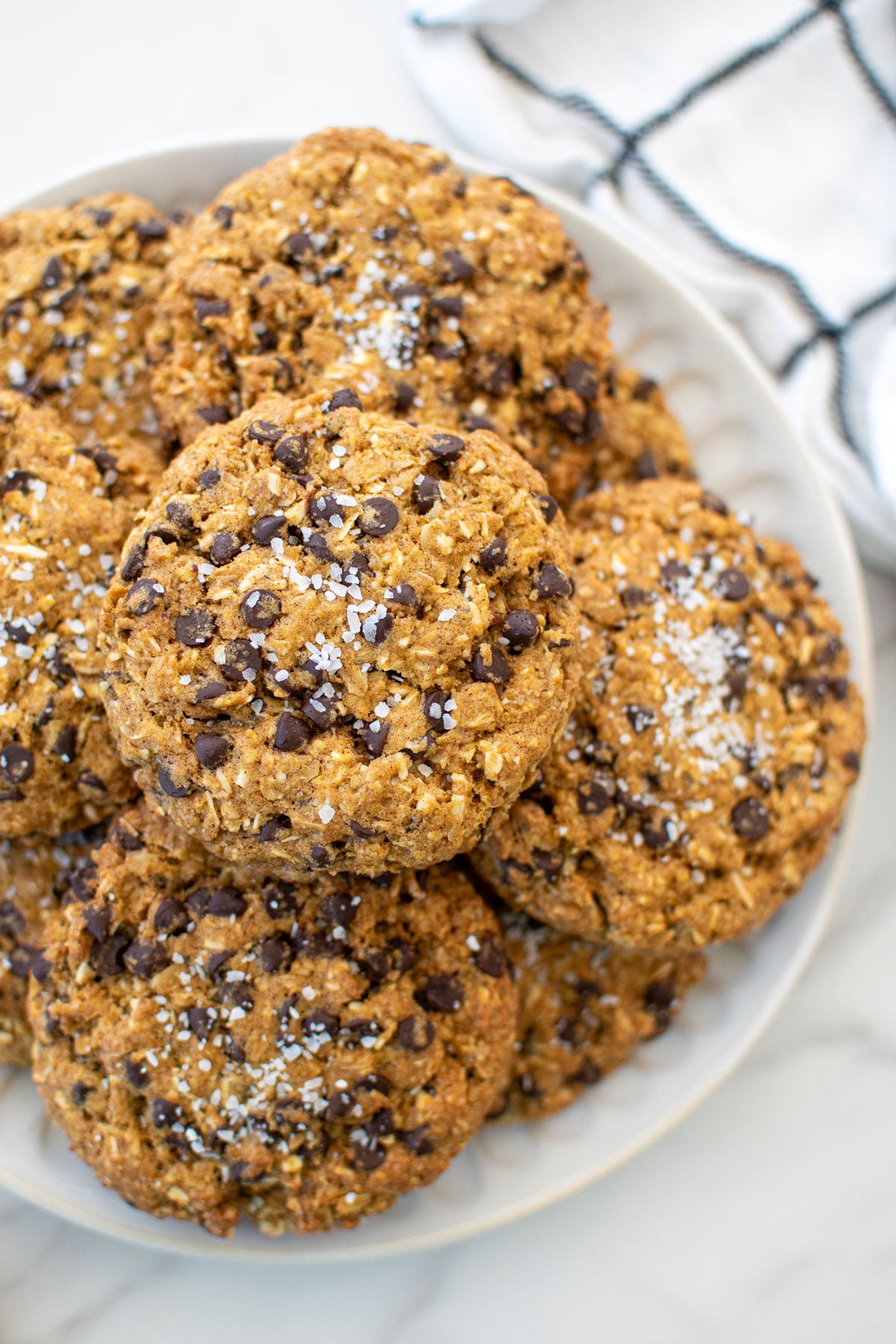 a plate of pumpkin oatmeal chocolate chip cookies on a white marble countertop.