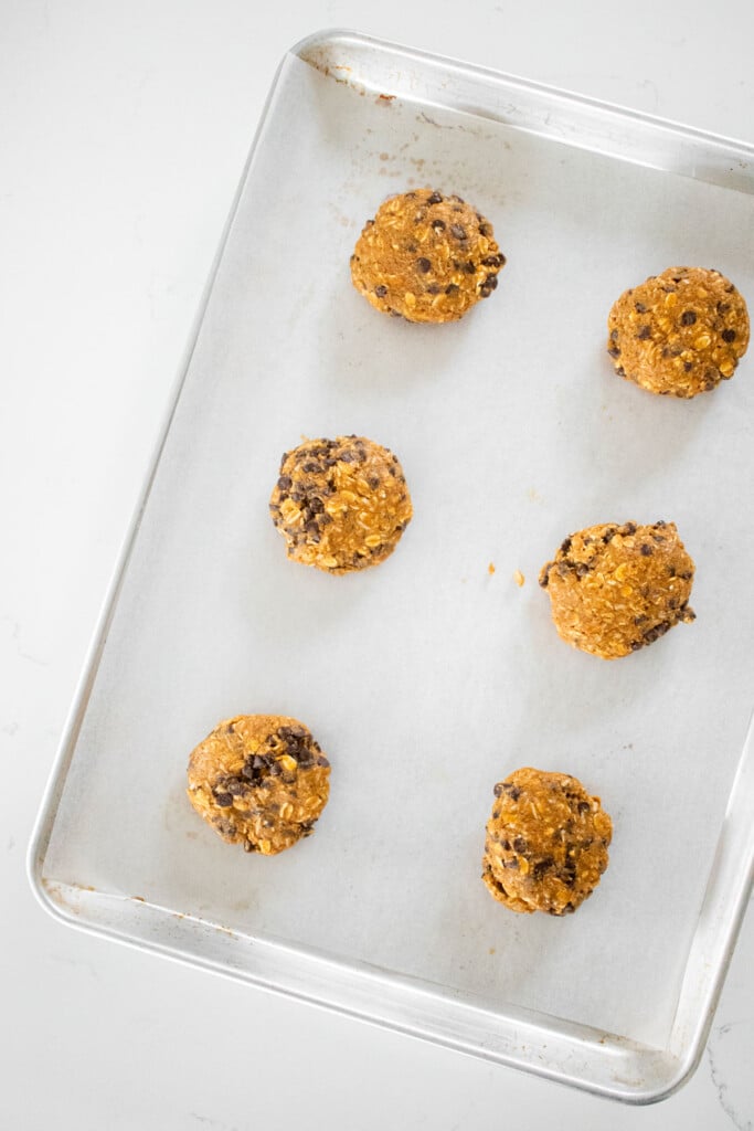 pumpkin oatmeal chocolate chip cookie dough balls on a baking sheet.
