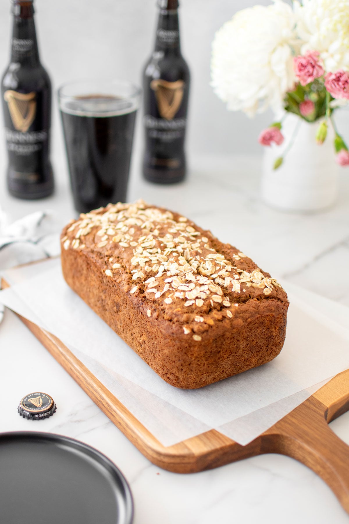 sourdough irish brown bread with guinness on a wood cutting board on a white marble counter.