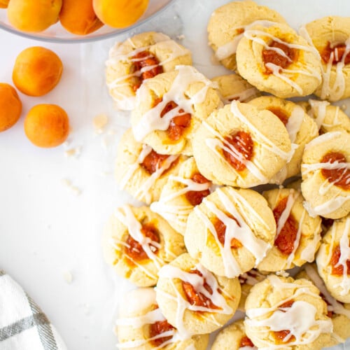 apricot jam thumbprints on a marble table with a bowl of apricots.