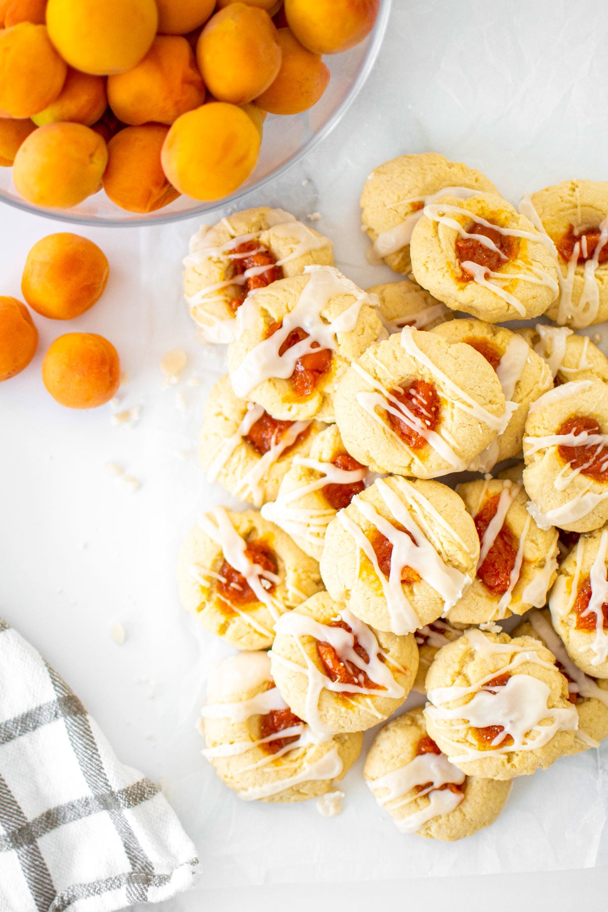 apricot jam thumbprints on a marble table with a bowl of apricots.